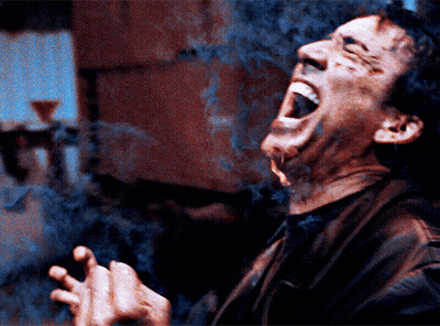 A Man Is Smoking A Cigarette With His Mouth Wide Open GIF