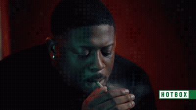 A Man Is Smoking A Cigarette With Smoke Coming Out Of His Mouth And A Hotbox Logo In The Corner . GIF