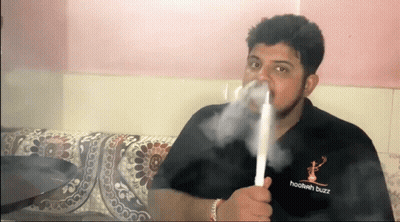 A Man Is Smoking A Hookah While Wearing A Hookah Buzz Shirt . GIF