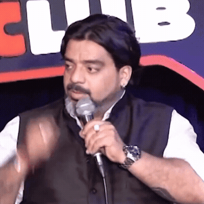 A Man Is Speaking Into A Microphone In Front Of A Club Logo GIF