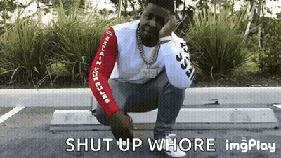 A Man Is Squatting Down In A Parking Lot With The Words Shut Up Whore Written Below Him . GIF
