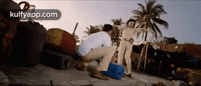 A Man Is Squatting Down In Front Of A Police Officer On A Beach . GIF