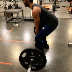 A Man Is Squatting Down To Lift A Barbell With A Plate That Says 20.4 On It GIF