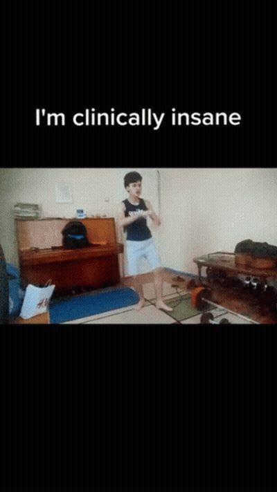A Man Is Squatting On The Floor In A Living Room With The Words " I 'M Clinically Insane " On The Bottom GIF