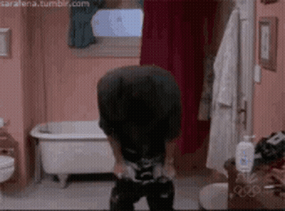 A Man Is Standing In A Bathroom With A Bathtub In The Background . GIF