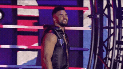 A Man Is Standing In A Boxing Ring Wearing A Black Vest And Smiling . GIF