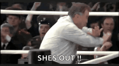 A Man Is Standing In A Boxing Ring With A Crowd Behind Him And Says `` She 'S Out ! '' GIF