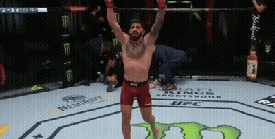 A Man Is Standing In A Boxing Ring With His Arms Up In The Air . GIF