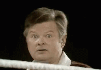 A Man Is Standing In A Boxing Ring With His Eyes Wide Open And Making A Funny Face . GIF