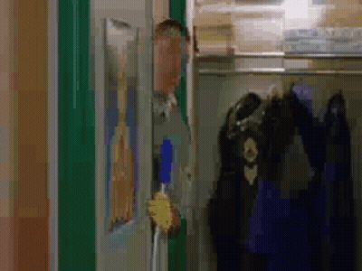 A Man Is Standing In A Closet Holding A Broom And Looking Out The Door . GIF
