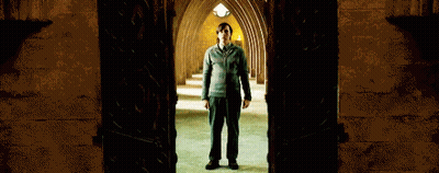 A Man Is Standing In A Dark Hallway With A Door Open GIF