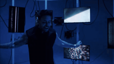 A Man Is Standing In A Dark Room Holding A Light GIF