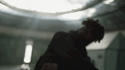 A Man Is Standing In A Dark Room With A Ceiling Light In The Background . GIF