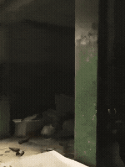 A Man Is Standing In A Dark Room With A Ladder GIF