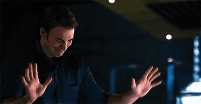 A Man Is Standing In A Dark Room With His Hands Outstretched And Smiling . GIF