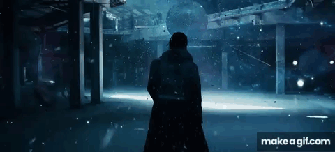 A Man Is Standing In A Dark Room With Snow Falling . GIF