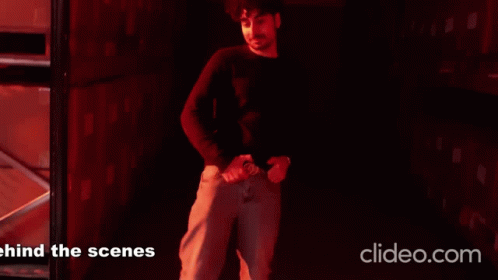 A Man Is Standing In A Dark Room With The Words Behind The Scenes On The Bottom Right GIF