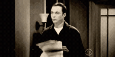 A Man Is Standing In A Doorway Holding A Stack Of Papers In His Hand . GIF