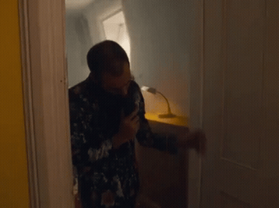 A Man Is Standing In A Doorway Talking On A Phone . GIF