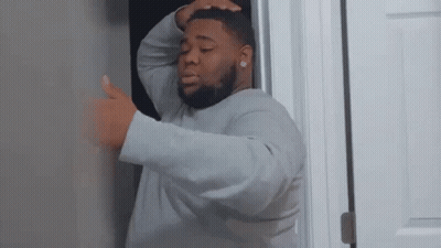 A Man Is Standing In A Doorway With His Hands On His Head . GIF