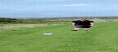 A Man Is Standing In A Field With A Remote Control Car . GIF