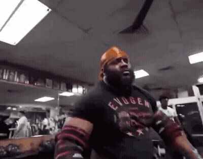 A Man Is Standing In A Gym Wearing A Bandana And A Black Shirt . GIF