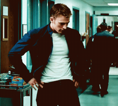 A Man Is Standing In A Hallway With His Hands On His Hips Wearing A White Shirt And A Blue Jacket . GIF