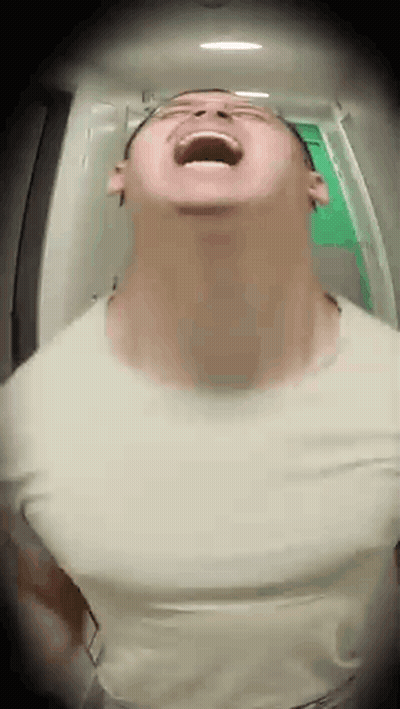 A Man Is Standing In A Hallway With His Mouth Open And Looking Up . GIF