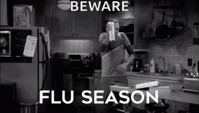 A Man Is Standing In A Kitchen Drinking From A Cup And Talking About Flu Season . GIF