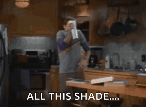 A Man Is Standing In A Kitchen Holding A Can Of Soda . GIF