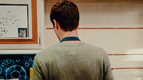 A Man Is Standing In A Kitchen Looking At A Picture Of A Cat On A White Board . GIF