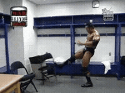 A Man Is Standing In A Locker Room Kicking A Chair In The Air . GIF