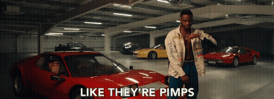A Man Is Standing In A Parking Garage With Cars And The Words Like They 'Re Pimps On The Bottom GIF