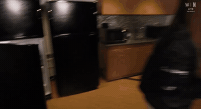 A Man Is Standing In A Refrigerator Looking Inside . GIF