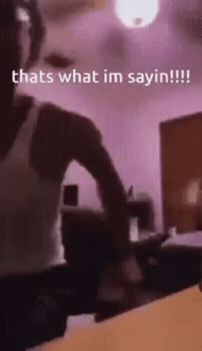 A Man Is Standing In A Room With A Ceiling Fan And A Purple Wall . GIF