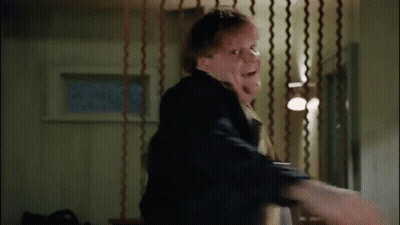 A Man Is Standing In A Room With A Curtain Behind Him And A Person Is Holding His Arm . GIF