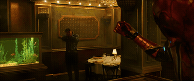 A Man Is Standing In A Room With A Table And A Lamp GIF
