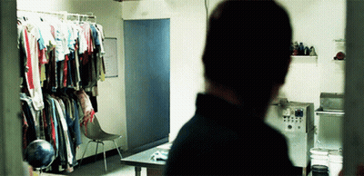 A Man Is Standing In A Room With Clothes Hanging On The Wall GIF