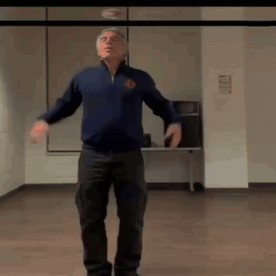 A Man Is Standing In A Room With His Arms Outstretched . GIF