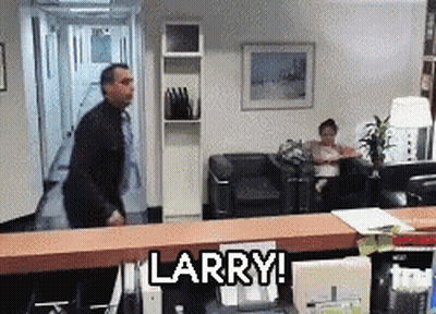 A Man Is Standing In A Waiting Room With The Words Larry On The Counter GIF