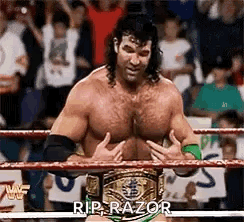 A Man Is Standing In A Wrestling Ring With A Championship Belt On His Chest . GIF