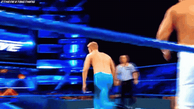 A Man Is Standing In A Wrestling Ring With A Referee Watching . GIF