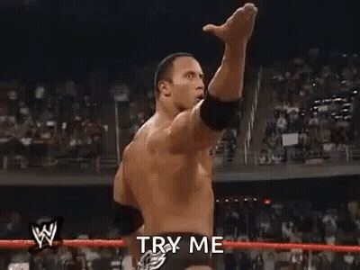 A Man Is Standing In A Wrestling Ring With His Fist In The Air And Says `` Try Me '' . GIF