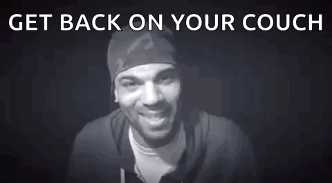 A Man Is Standing In Front Of A Black Background With The Words `` Get Back On Your Couch # Blocked '' . GIF