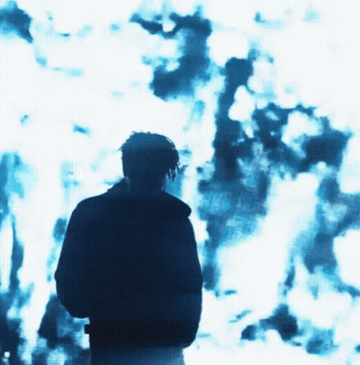 A Man Is Standing In Front Of A Blue Background GIF