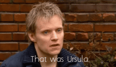 A Man Is Standing In Front Of A Brick Wall And Says That Was Ursula . GIF