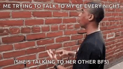 A Man Is Standing In Front Of A Brick Wall And Talking To His Gf . GIF