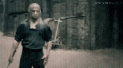 A Man Is Standing In Front Of A Brick Wall Holding A Knife . GIF