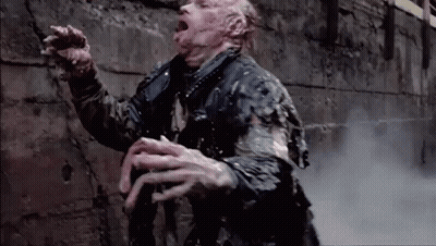 A Man Is Standing In Front Of A Brick Wall With His Mouth Open And Smoke Coming Out Of His Mouth . GIF