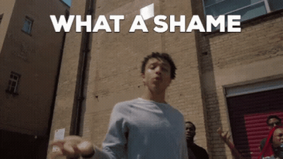 A Man Is Standing In Front Of A Brick Wall With The Words What A Shame Written Above Him GIF